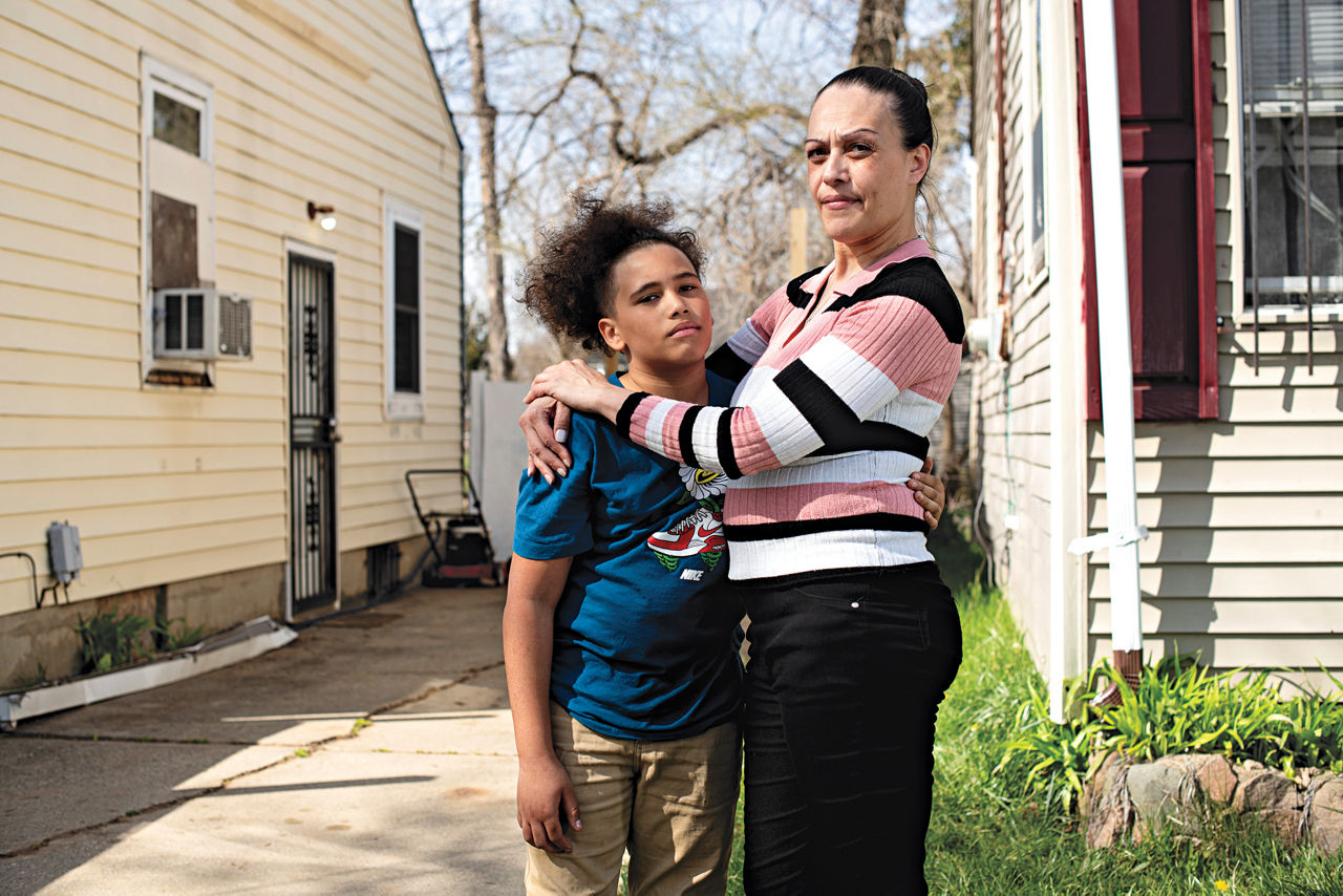 A mother standing with her hands wrapped around her son.