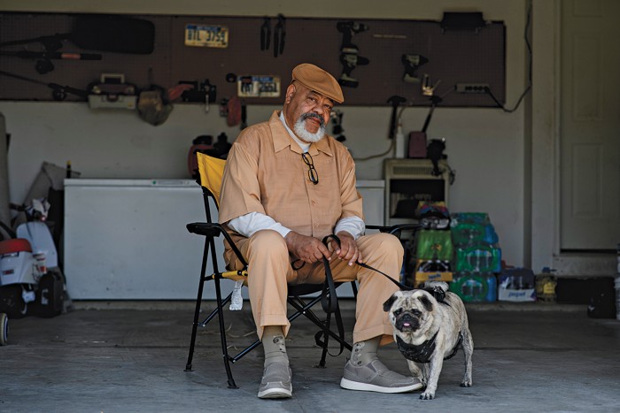Man sitting on a chair with a dog by his side.