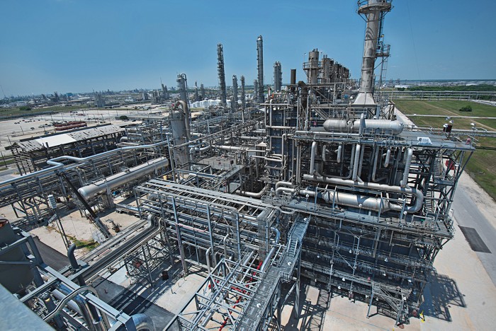A LyondellBasell Industries chemical plant during the day, as visible from a high point. There is metal scaffolding and steam fitting work.