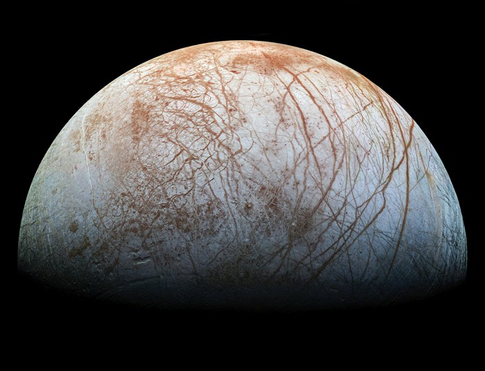 Europa weist eine weiß und rot gesprenkelte Oberfläche auf, die mit dunkelroten Kratzern bedeckt ist.