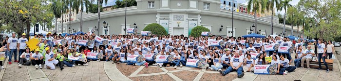 A very large group of smiling people wear matching T-shirts.