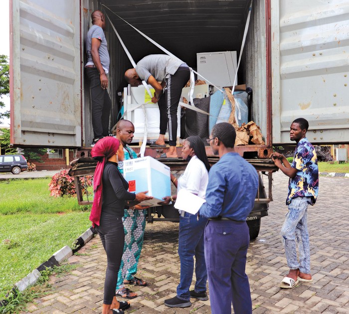 A group of seven people unloading boxes from a box truck and reading their labels.