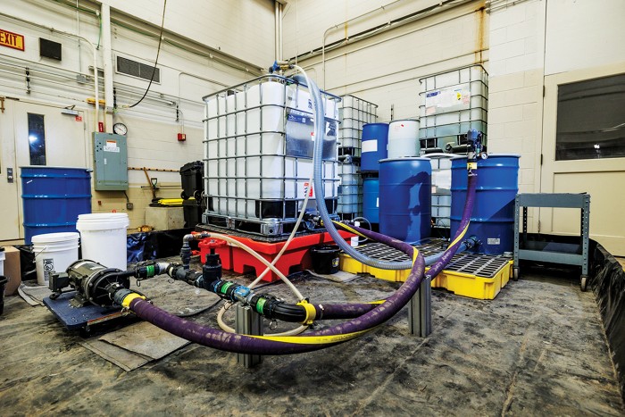 Steel drums containing granular activated carbon are connected with hoses to a plastic tote containing solvent and a vacuum pump.