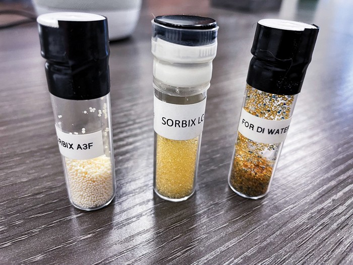 Glass vials with tiny plastic resin beads used in ion-exchange filters.