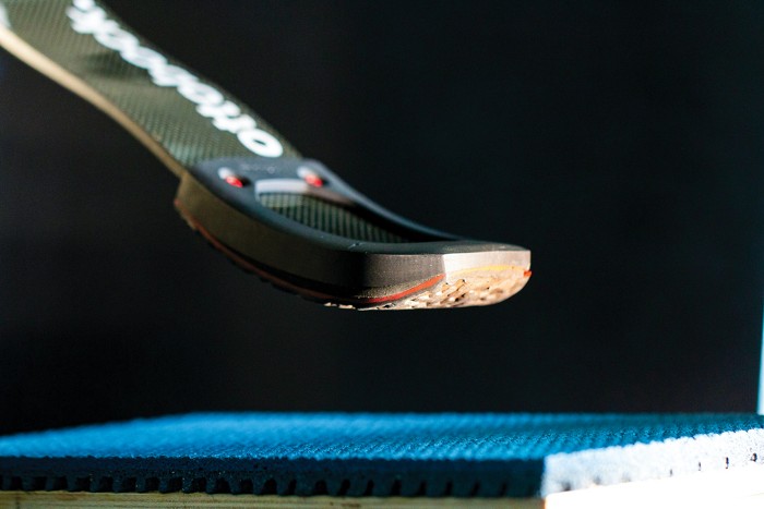 A close-up of the underside of a jumping knife against a dark background.