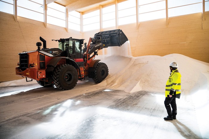 A loader scoops sodium sulfate, a white powder, off the floor of a warehouse.