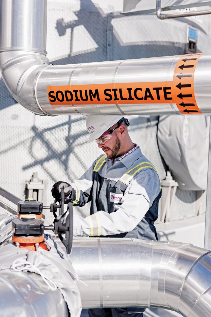 A man working in Evonik Industries’ silica plant in Charleston, South Carolina. He is wearing protective gear and working near a pipe that says 