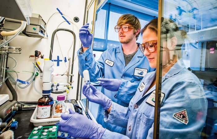 Two scientists hold test tubes inside a chemistry lab.