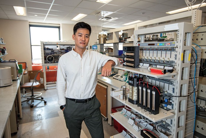 A scientist stands next to a rack with batteries charging.