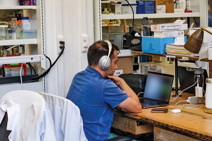 A scientist using their laptop and headphones in the main coworking area at the Harlem Biospace.