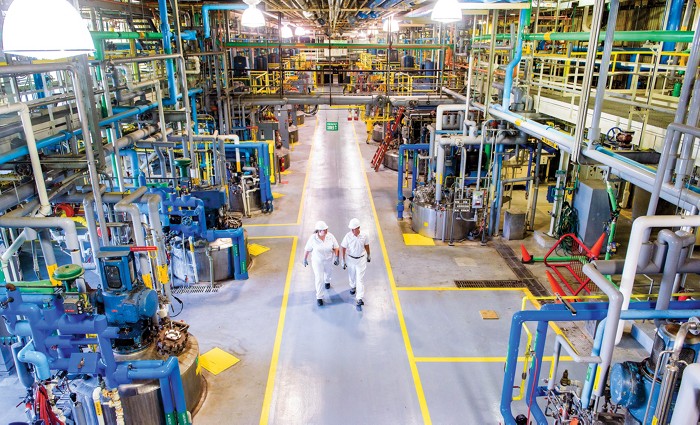 Two employees walk through the fermentation hall at a chemical plant.