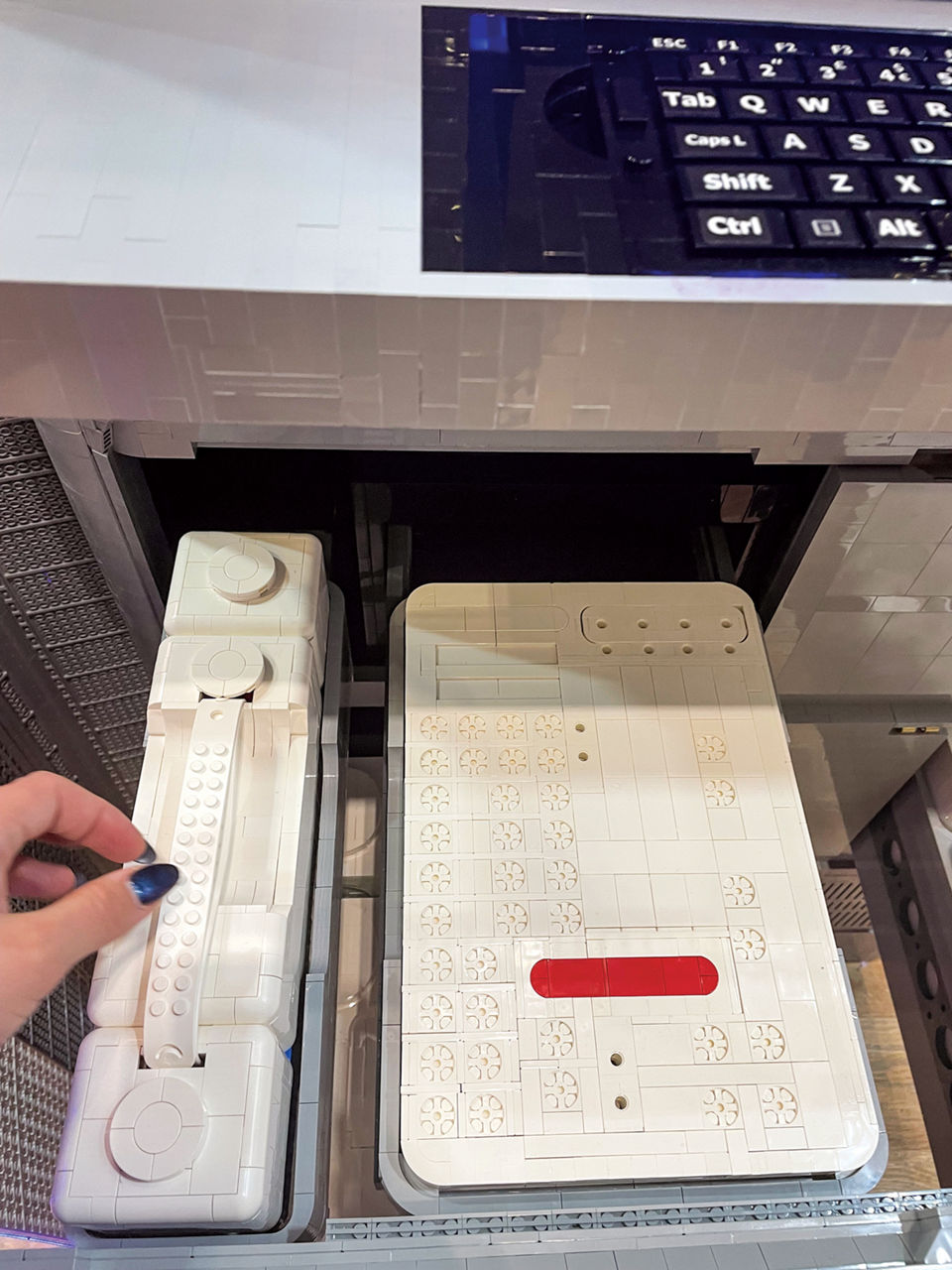 A viewer interacts with the Lego reagent containers inside the drawers of a Lego replica of one of Illumina's NovaSeq X sequencers.
