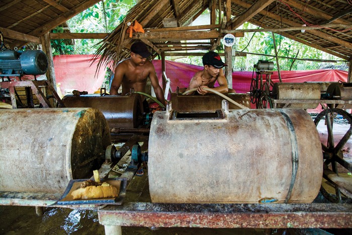 Workers behind drums at a small gold processing plant.
