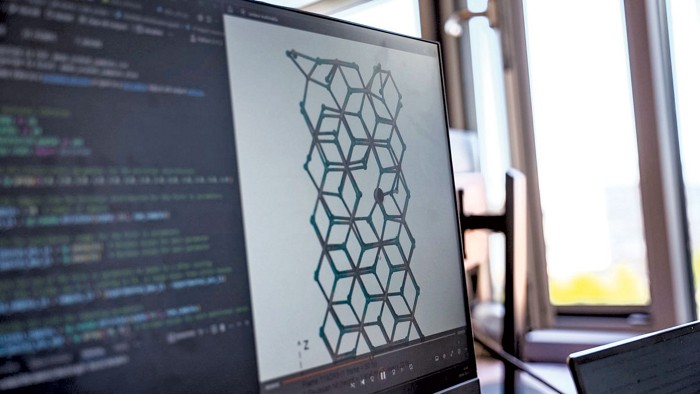 A computer monitor showing some coding and an image of 3D boxes connected together.