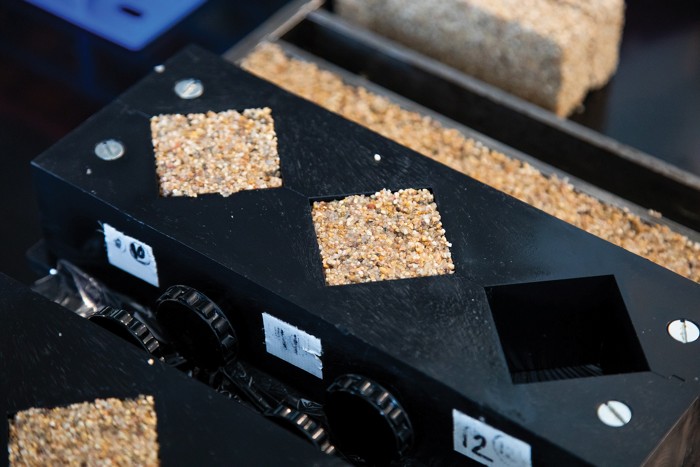 A black mold is shown in the center with three diamond-shaped holes; two of the holes are filled with brown particulate material.