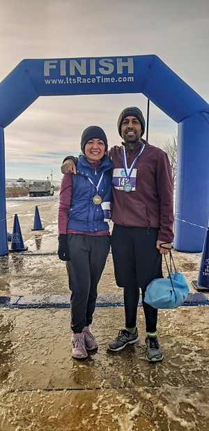 A couple in running clothes stands at the finish line of a race.