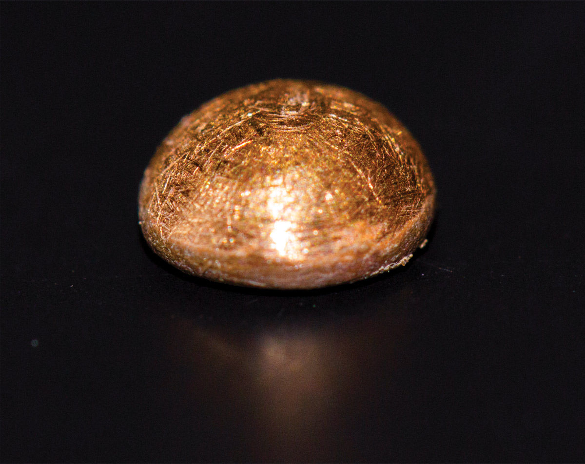 Close up photograph of a small, rounded mound of gold, made from stringy fibers.