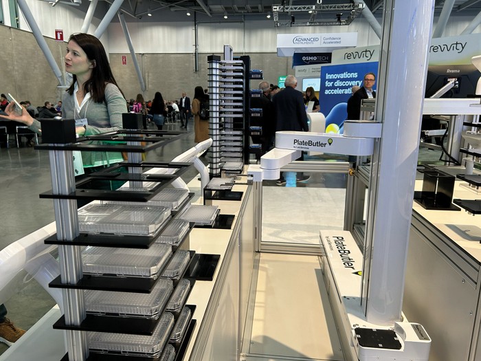 A robotic arm picks up a microtiter plate to move it from one shelf to the next.