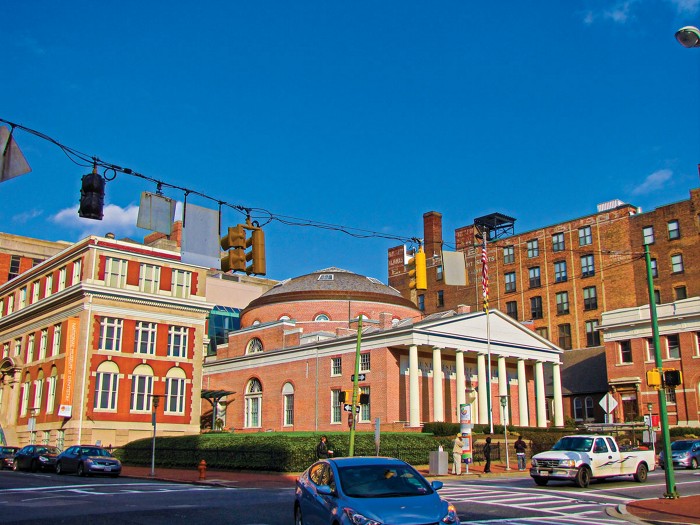 An exterior shot of red brick buildings. One has a domed roof and classical columns at the front.