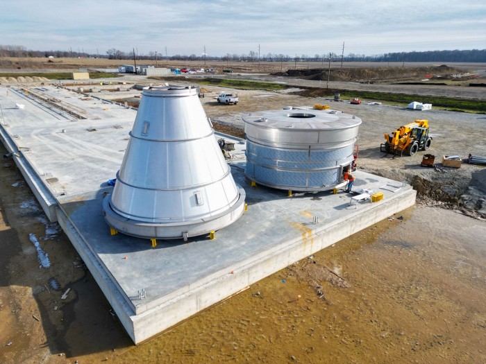 Equipment for a large fermenter sits on a concrete pad in a construction zone.