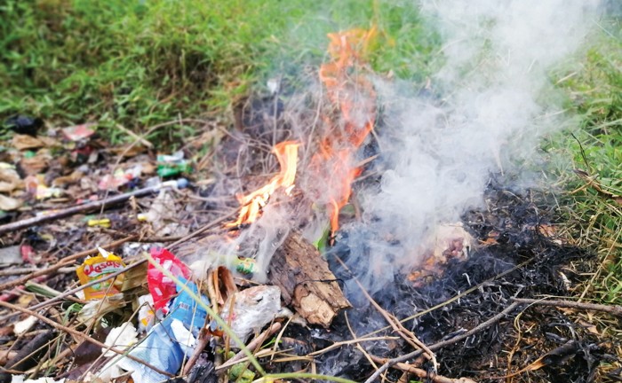 Trash burning in a small fire in a grassy field.