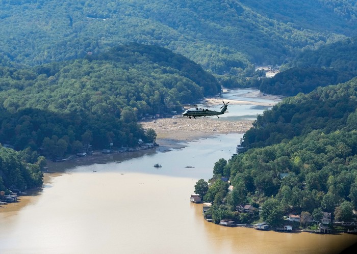 A helicopter flies over a flooded area.