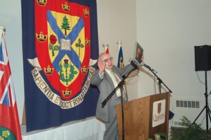 A man stands behind a podium making hand gestures as he speak.