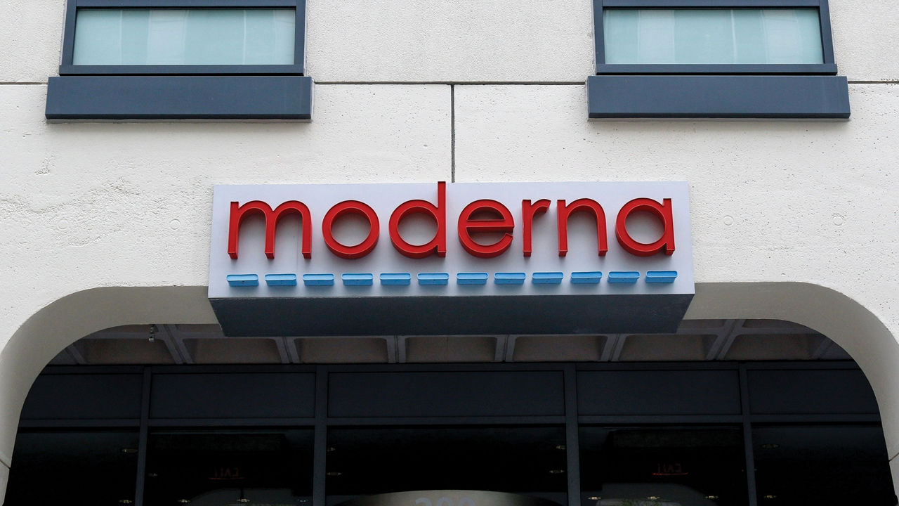 A sign with red letters spelling “Moderna” hangs over a building entrance.