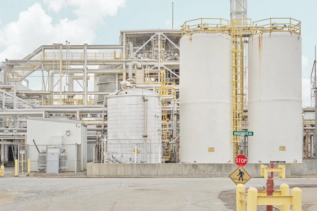 White tanks and piping stand against a cloudy, pale-blue sky.