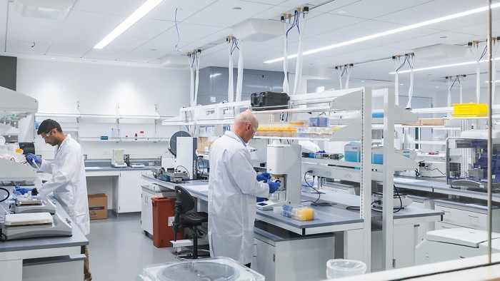 Duas pessoas em casacos de laboratório trabalhando em um laboratório.