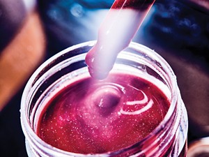 Um close de um pote de um cosmético lábio vermelho.