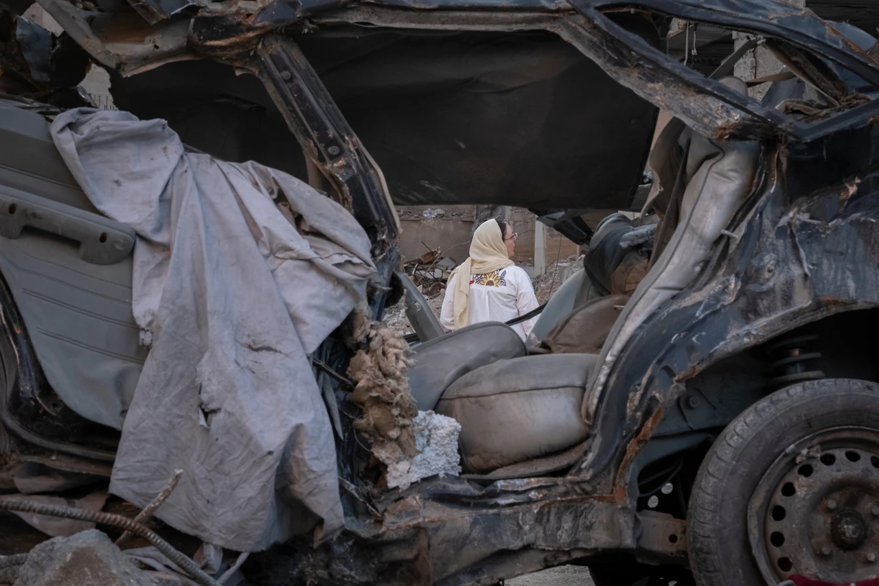 A woman stands behind a vehicle destroyed in a strike while visiting a residential area that was struck on March 9 in Tehran, Iran, on April 9, 2026. (Photo by Morteza Nikoubazl/NurPhoto via AP)