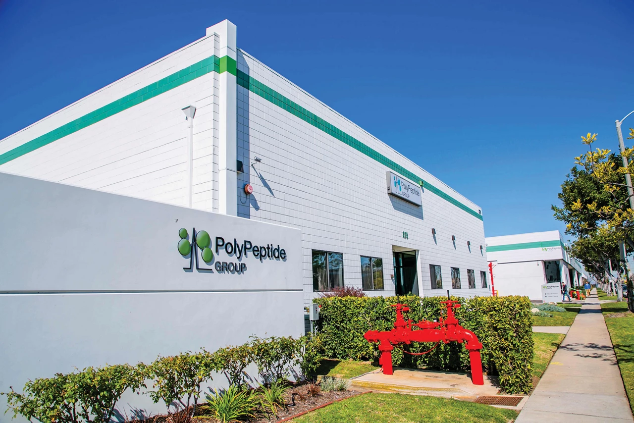 A low, white building with a PolyPeptide Group sign.