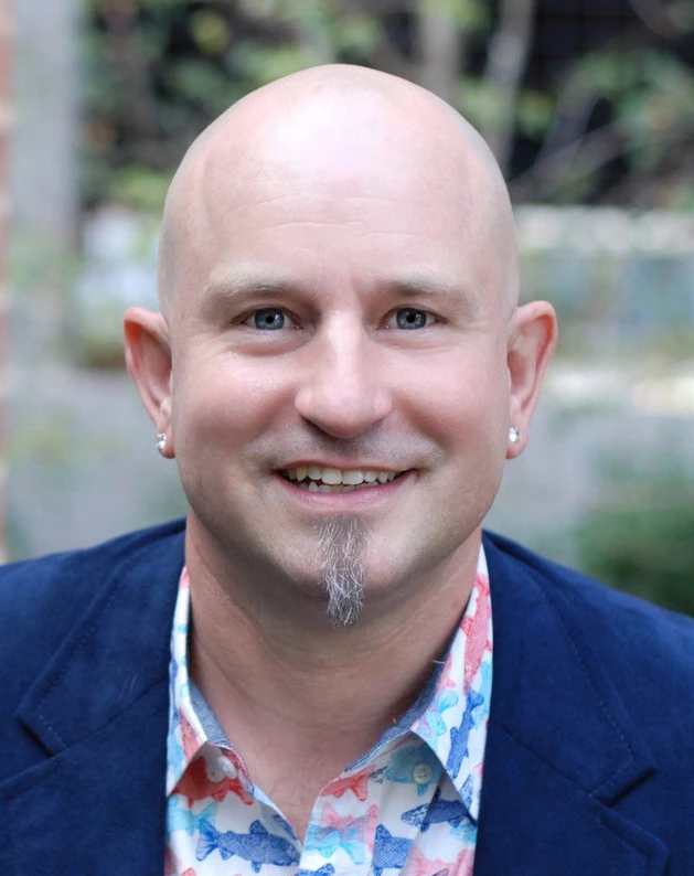 A person poses in business casual attire.