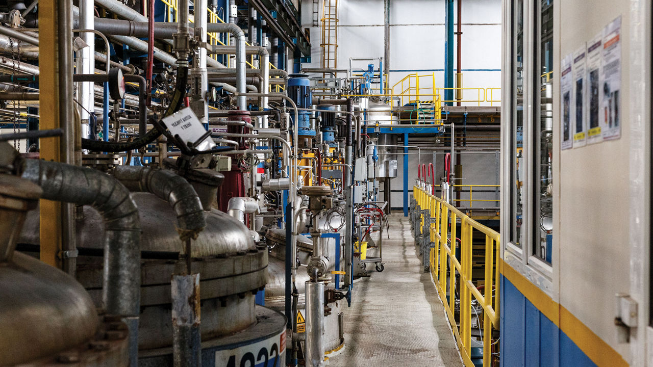 Tops of several reactor vessels extend through a floor in a chemical plant.