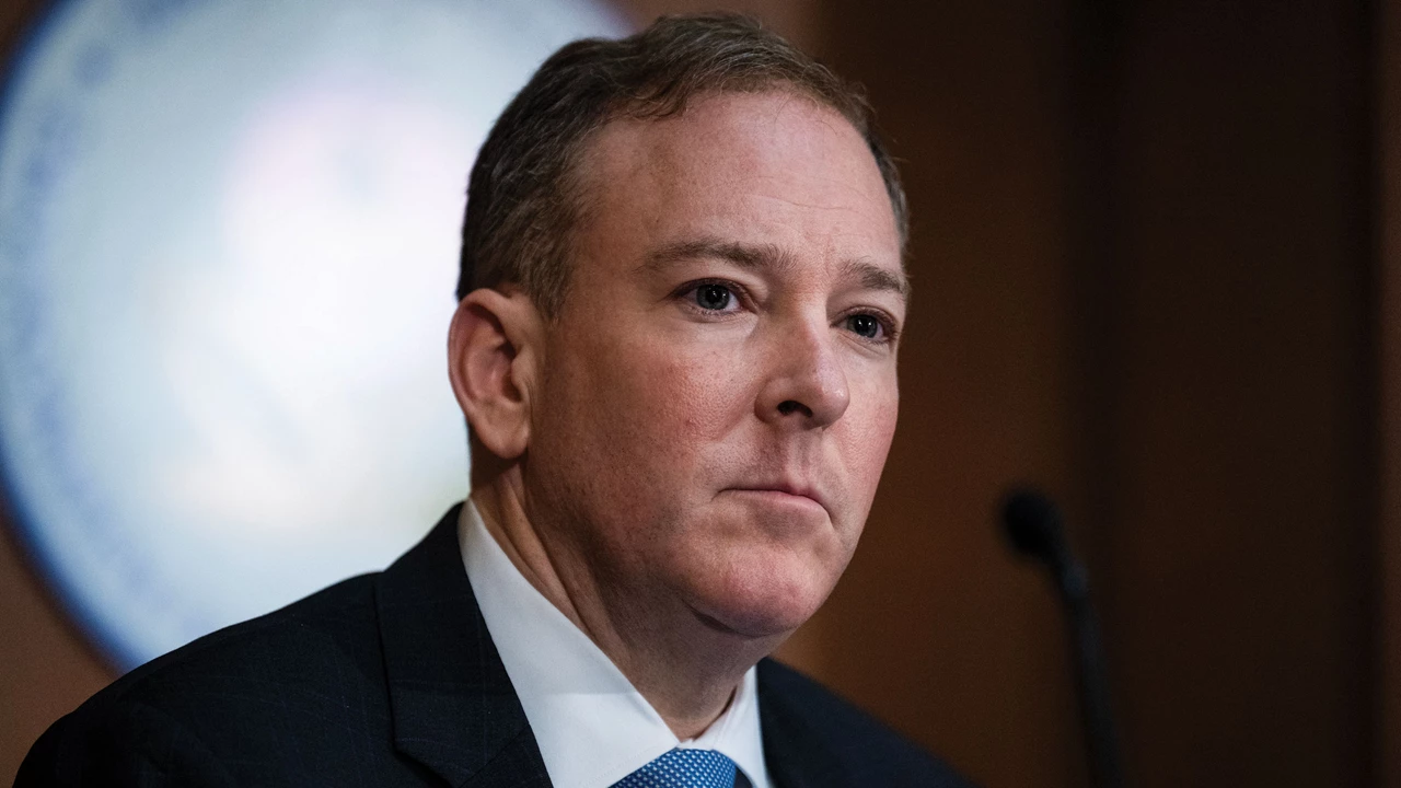 Lee Zeldin wears a blue suit jacket, a blue tie, and a white shirt.