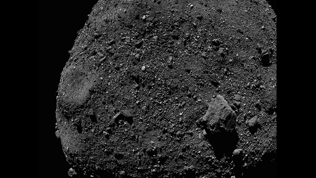 A video shows a dark rocky surface. At the beginning, the camera pans from the surface to the horizon, beyond which is blackness. The video fades and then shows the approaching surface, collision, and eruption of dark rocky material.