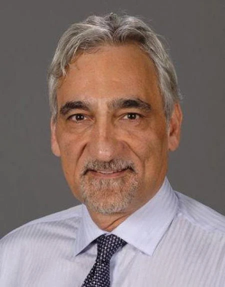 A man wearing a dress shirt and a polka-dot tie poses for a portrait shot.