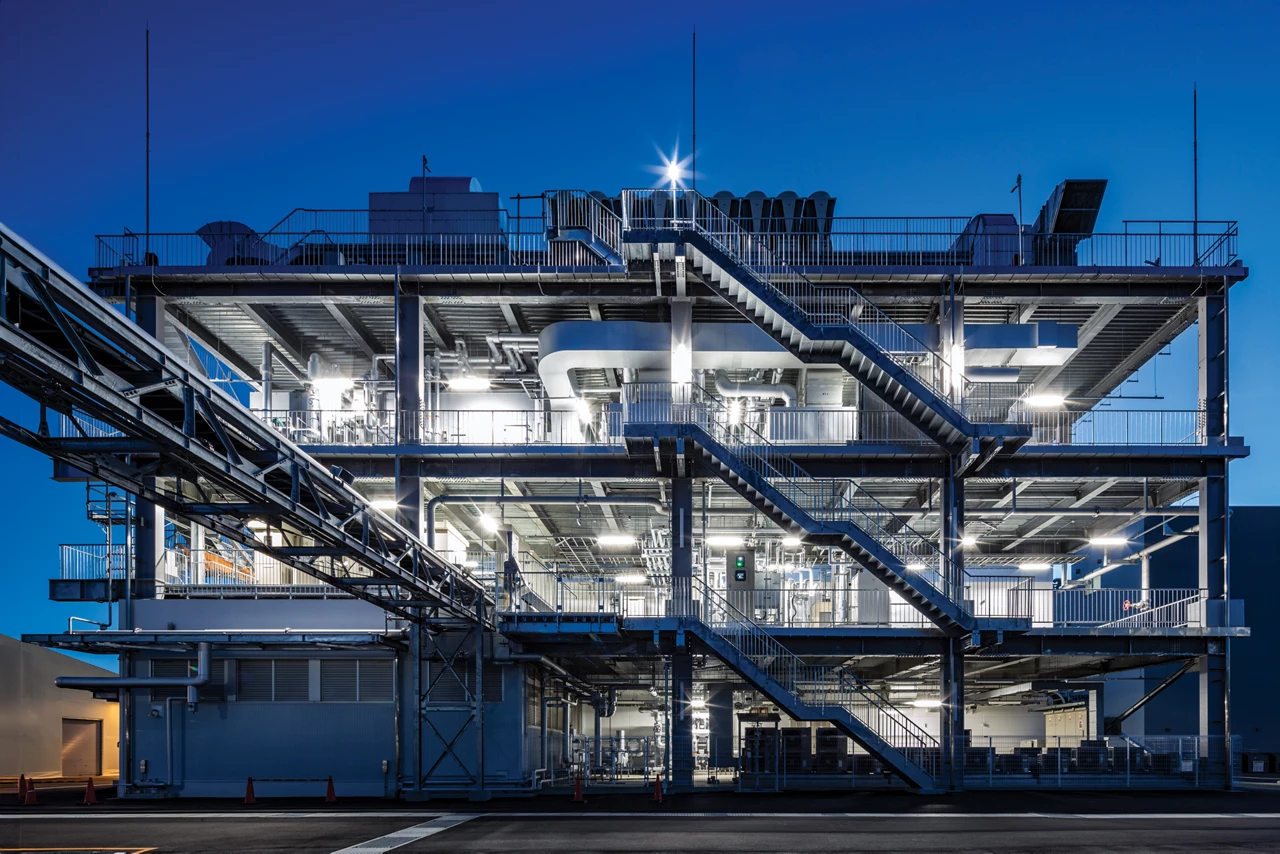 A chemical plant at night, in which the interior of the scaffolding radiates white light.