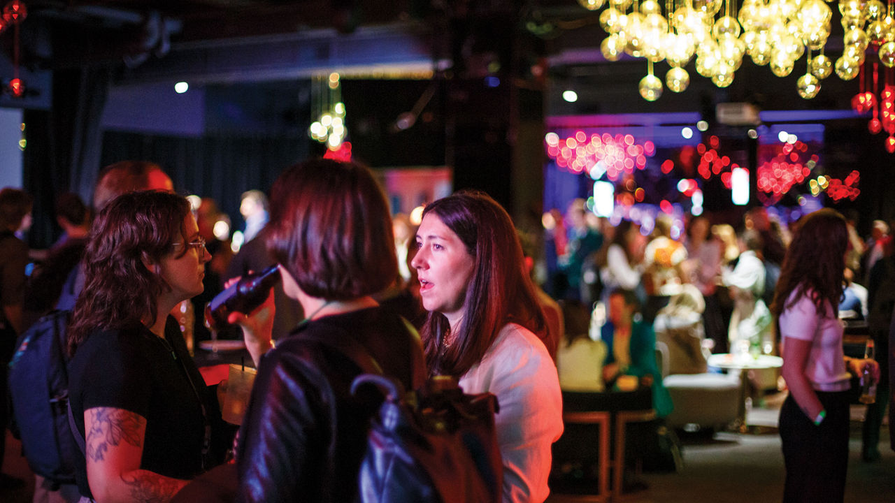 A crowd of people in a dramatically lit events venue.