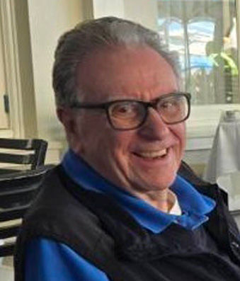 <i>James G. Speight wears a blue top and glasses and smiles at the camera</i><i><u>.</u></i> 