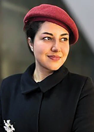 Anam Murad Khan, wearing a black top and a maroon beret, poses for a portrait.