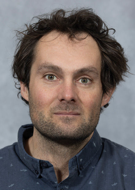 David Frazer, wearing a dark-blue shirt decorated with small fish icons, poses for a portrait.