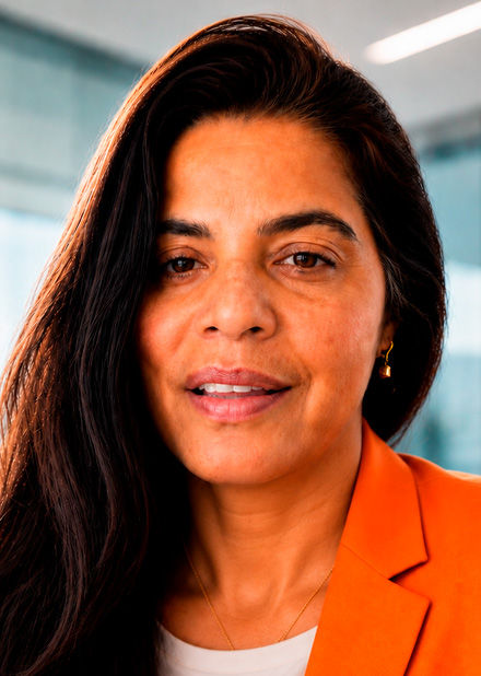 Punam Thakur, wearing a white shirt and an orange jacket, poses for a portrait.
