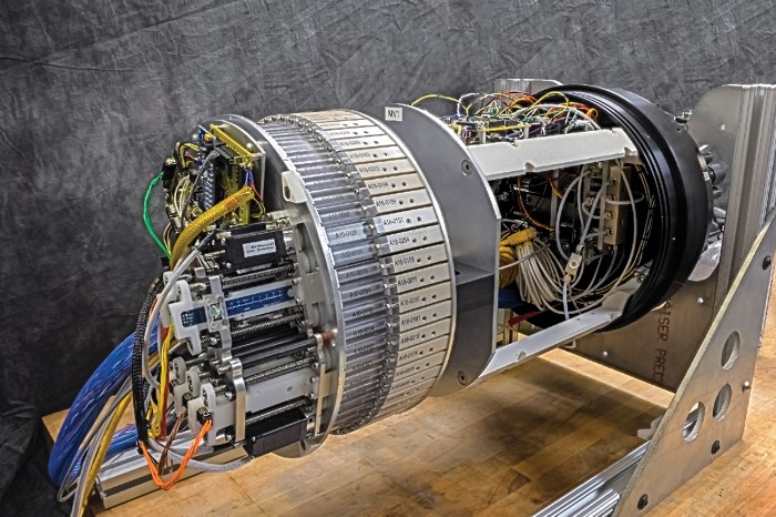 The interior equipment of a Monterey Bay Aquarium Research Institute autonomous vehicle sits on a table, exhibiting a tangle of wires and pumps and a large barrel surrounded by dozens of sample containers.