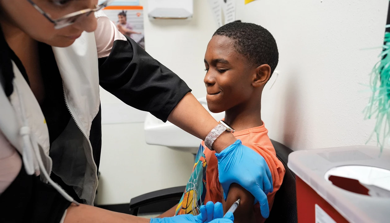 A young boy gets a vaccine in his left arm in an immunization clinic.