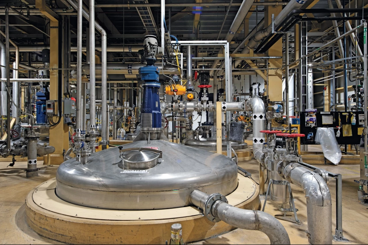 Two workers move a 100 L glass reactor through Nano One's Montreal lithium iron phosphate factory.