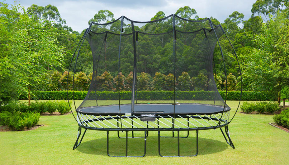 A large trampoline with an enclosure in a backyard.