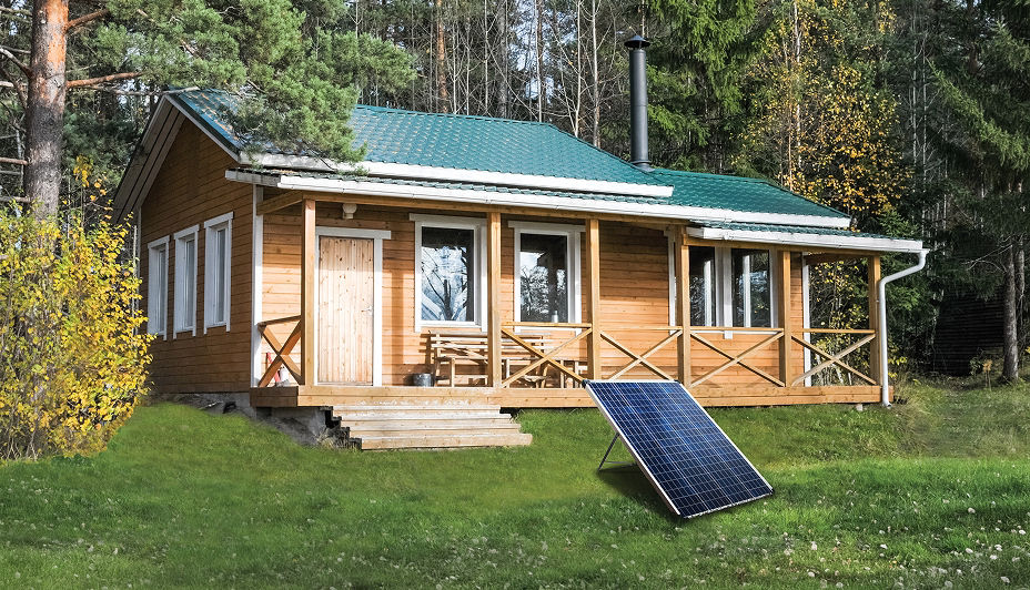 A brown wooden cottage with a NOMA 100W solar kit sitting on the lawn surrounded by trees.