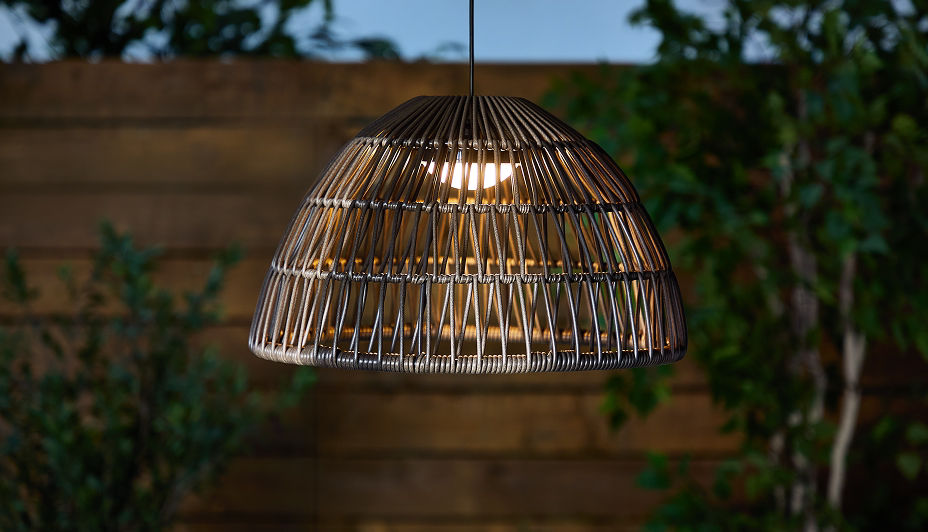 A hanging wicker solar light in a backyard patio.